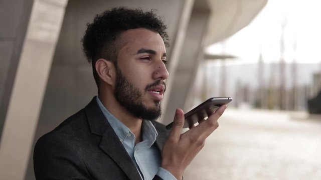Confident man with bristle talking on smartphone outdoor.