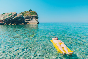 young man at yellow inflatable mattress in clear transparent water