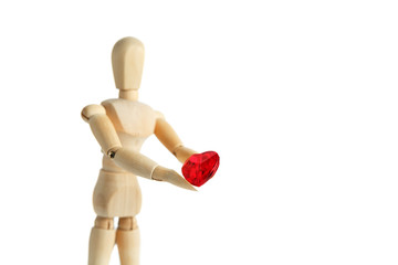 The wooden figure of a man holds in his hands a red heart on a white background. Gives the heart