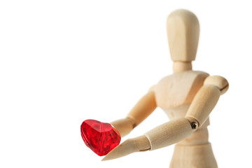 The wooden figure of a man holds in his hands a red heart on a white background. Gives the heart