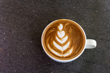 Latte art coffee cup on dark background textured