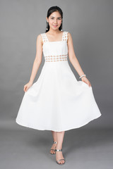 Naklejka premium Beautiful woman in white dress portrait in studio, grey background