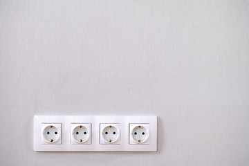 Four power sockets on gray wall.