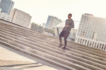Sport in my life. Full length portrait of athletic african man in sportswear jogging down stairs in the urban environment on a sunny warm day. Cardio training.