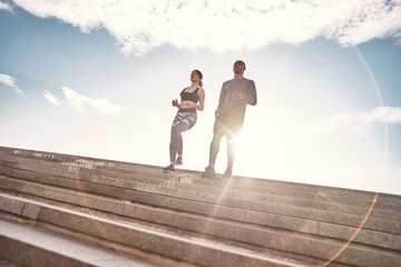 Obraz premium Training together is fun. Full length portrait of cute and young interracial couple in sportswear running down stairs against sunny and clear sky. Common hobbies
