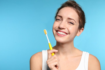 Obraz na płótnie Canvas Portrait of young woman with toothbrush on color background. Space for text