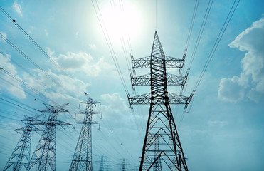 High voltage towers against blue sky on sunny day