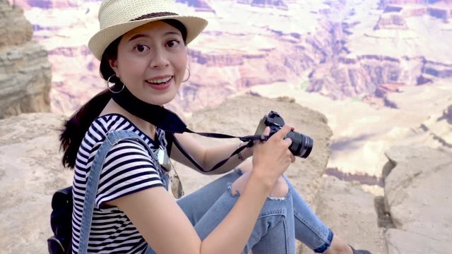 fast movement of young asian woman tourist taking picture on top of mountains in Grand Canyon National Park sightseeing desert view. beautiful charming girl in straw hat photographing friend in back