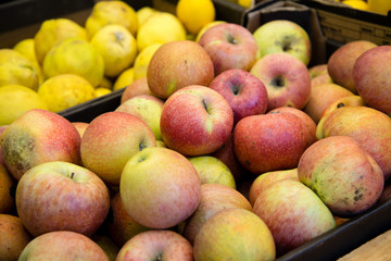 fresh fruit, many ripe red apples on the counter in the supermarket
