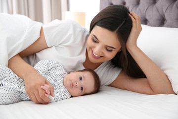 Happy woman with her cute baby on bed