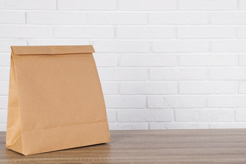 Paper bag on table against brick wall. Mockup for design