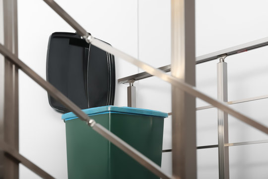 Trash bin on stair landing indoors. Waste recycling