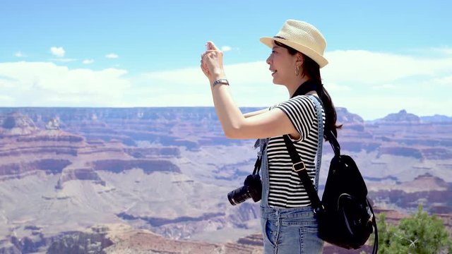 Hiking tourist recording video of desert view by cellphone in Grand Canyon at hike by south rim by Bright Angle trail. Young asian woman hiker enjoying nature landscape in Grand Canyon Arizona USA.