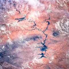 The Colorado River through the clouds and arid terrain of southeastern Utah, satellite view. Elements of this image furnished by NASA.