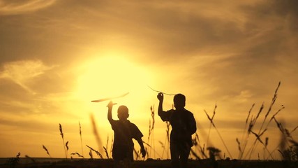 Silhouette of two boys running with airplanes at sunset