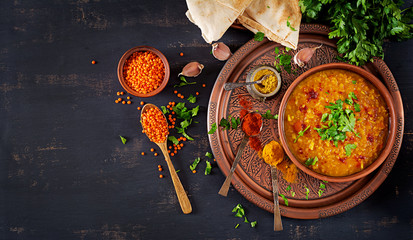 Indian dal. Food. Traditional Indian soup lentils.  Indian Dhal spicy curry in bowl, spices, herbs, rustic black wooden background. Top view. Authentic Indian dish. Overhead. Flat lay