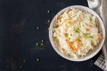 Fermented cabbage. Vegan food. Sauerkraut with carrot and spices in bowl on the dark background. Trend food. Top view . Flat lay, copy space
