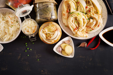 Fermented food. Vegetarian food concept. Cabbage kimchi, tomatoes marinated, sauerkraut sour glass jars over rustic kitchen table. Canned food concept. Top view. Flat lay