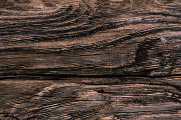 old weathered dark brown cracked wooden knotted boards close-up