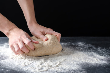 Woman kneading dough on sprinkled with flour table. Yeast dough for bread, rolls, pizza, focaccia or pie. Homemade dough. Design for text.