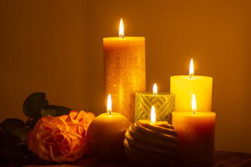 Fototapeta na wymiar Six burning candles and roses, warm colors, feelings and memory, soft warm colors close up