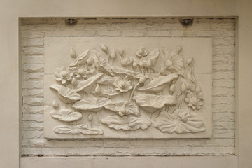 Beautiful white lotus stucco patterned on the boundary wall. Vintage white wall bas-relief stucco in plaster, depicts Lotus flowers background.
