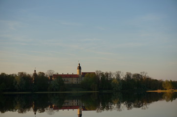 Fototapeta na wymiar Nesvizh Castle in autumn as seen from across the pond. Minsk Region, Belarus. Site of residential castle of the Radziwill family. 