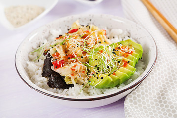 Vegan salad  with rice, pickled kimchi cabbage, avocado,  nori and sesame on bowl. Sushi-food hybrids trend. Overhead