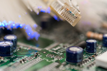 Internet switch on focus, glowing optical fibres on computer circuit board macro shot.