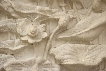 Beautiful white lotus stucco patterned on the boundary wall. Vintage white wall bas-relief stucco in plaster, depicts Lotus flowers background.