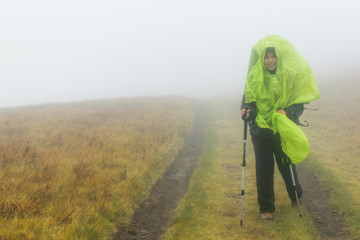 Woman with backpack hiking in the fog.