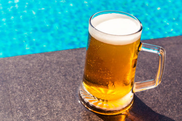 A glass of beer on a sunny day by the pool