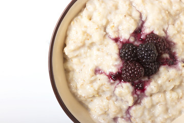 Healthy breakfast with a glass of milk, homemade oatmeal with blackberries in a blue bowl and fresh cereal bread on a light background