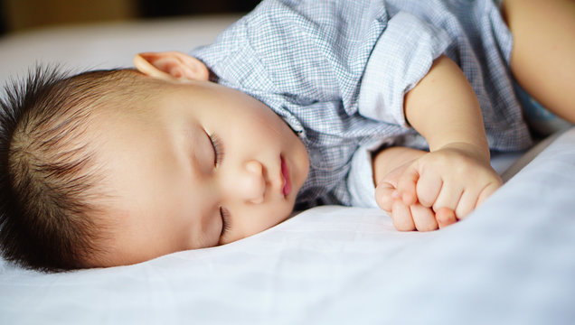 Toddler kid sleeping peacefully on white bed
