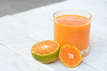 a glass of orange juice and fresh oranges on white wooden base
