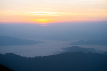 The sunrise at the mountain with the fog and cloud cover it.