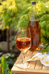Cold rose wine in glasses served on outdoor terrace in garden with flowers in sunny day
