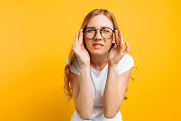 A girl with poor eyesight wears glasses, looking squinting, trying to figure out what is written on a yellow background - obrazy, fototapety, plakaty