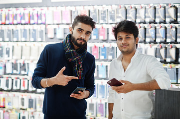 Two indians mans customer buyer at mobile phone store with them new smartphones. South asian peoples and technologies concept. Cellphone shop.