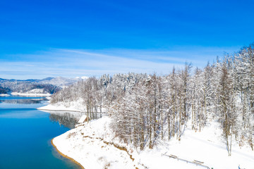      Beautiful winter panoramic landscape in mountains, Lokvarsko lake in Croatia, woods under snow in Gorski kotar and Risnjak mountain in background from drone 