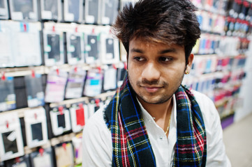 Indian man customer buyer at mobile phone store sitting on chair. South asian peoples and technologies concept. Cellphone shop.