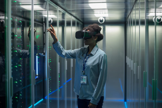 Technician works in a data center wearing a VR headset - Powered by Adobe