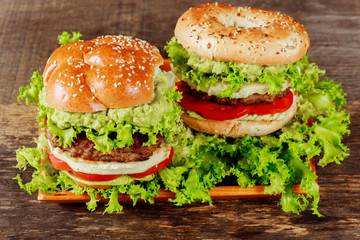 Guacamole beef burger with melted cheese on wooden background