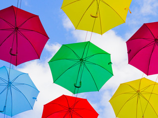 colorful umbrellas, white, blue, green, red and yellow against the background of the summer sky,...