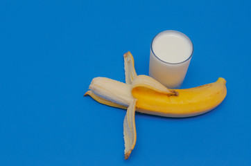 Ripe banana and a glass of yogurt on a blue background. The concept of healthy eating.