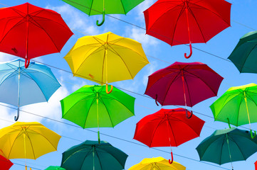 colorful umbrellas, white, blue, green, red and yellow against the background of the summer sky, umbrellas of different colors from the sun