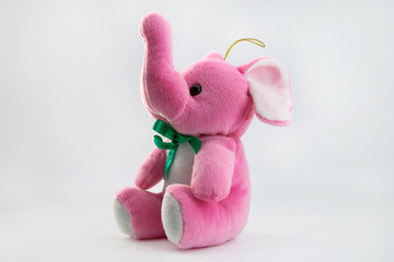 Soft toy pink elephant sitting isolated on white background. 