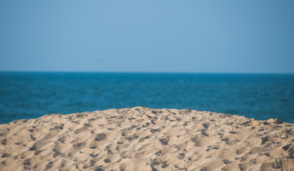 Fototapeta na wymiar Beach Scene With Sand Blue Water And Blue Sky
