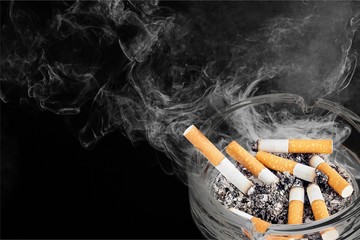 Ashtray and smoked cigarettes on backgrouund