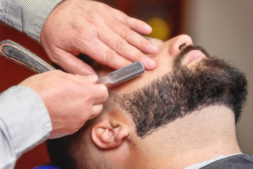 Obraz na płótnie Canvas Handsome man having a shave with vintage razor at the barbershop .